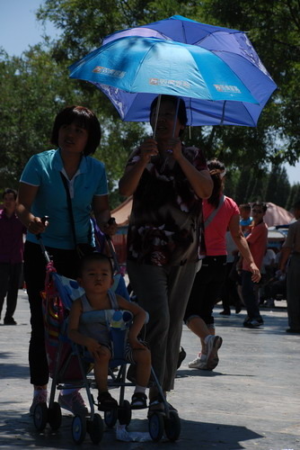 7月5日，时至正午，接近40度的高温下，故宫内的游客靠两把伞才勉强撑起一片阴凉地。实习生 卢翼 摄 
