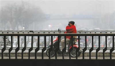 光明桥，骑车男子用手捂嘴通过二环，当日京城雾霾继续。