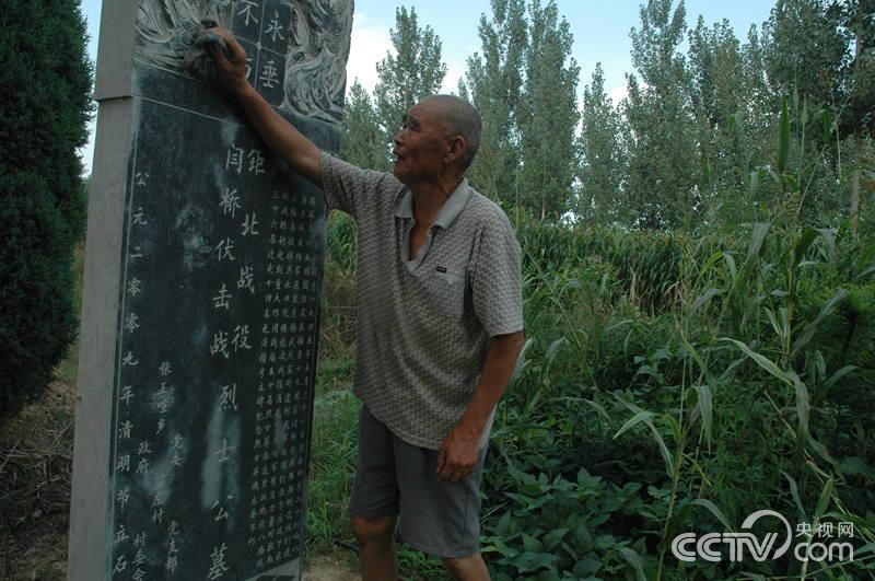 苗明文在擦拭“八路坟”墓碑上的尘土